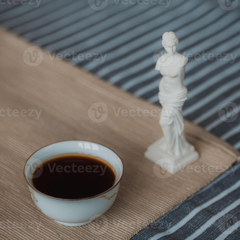 A Thoughtful Composition of Delicious Coffee and a Beautiful Statue in Still Life photo