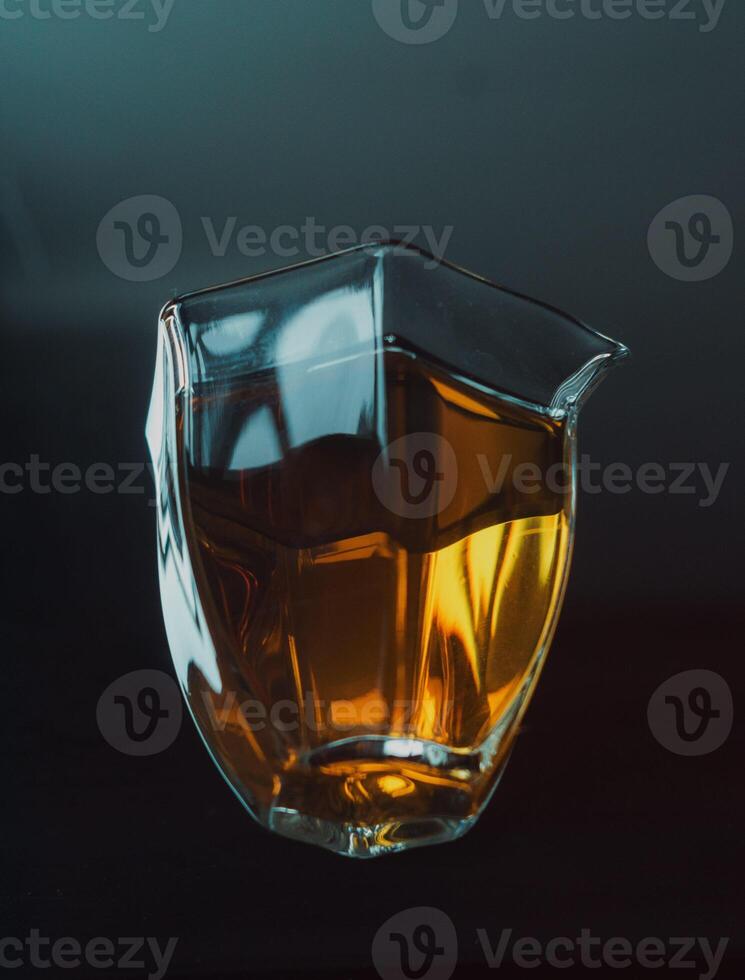 An Elegant Glass Pitcher Filled with Amber Liquid Set Against a Dark Background for Contrast photo