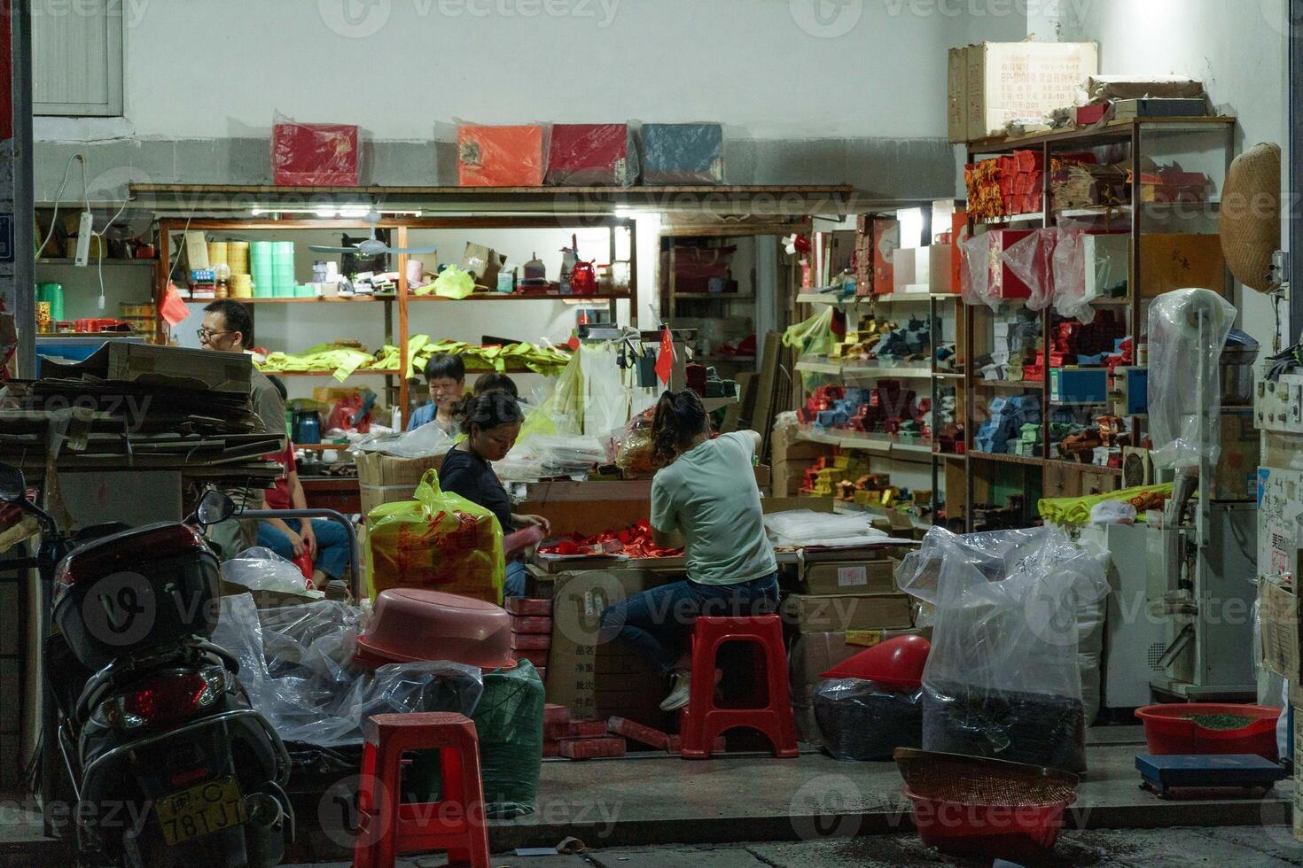 A vibrant evening scene unfolds in a bustling local shop filled with colorful goods and bags photo