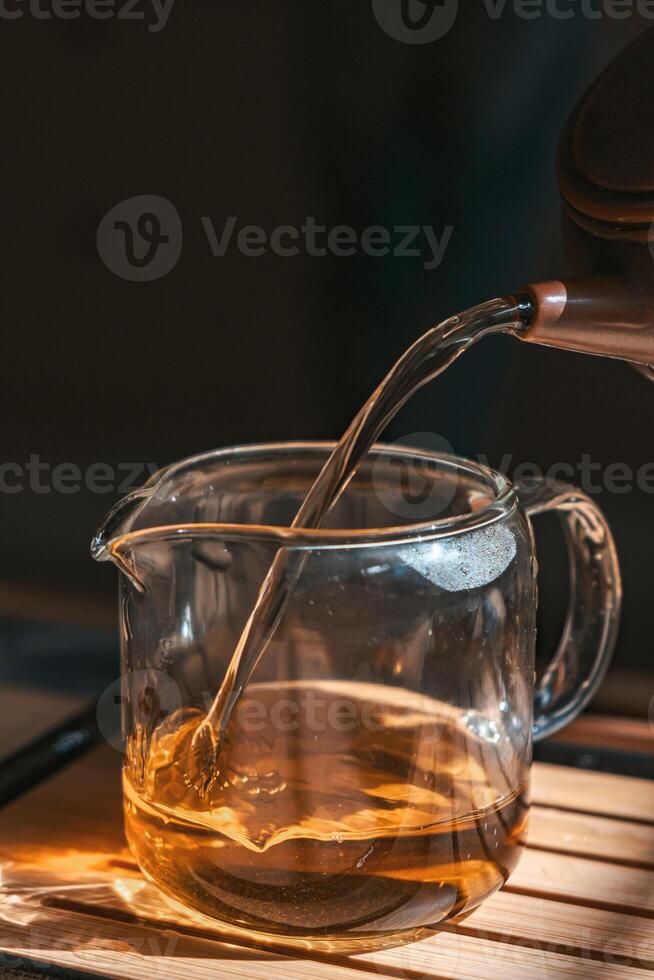 Pouring a Steaming Hot Cup of Tea into a Clear Glass Jug for Enjoyment and Comfort photo