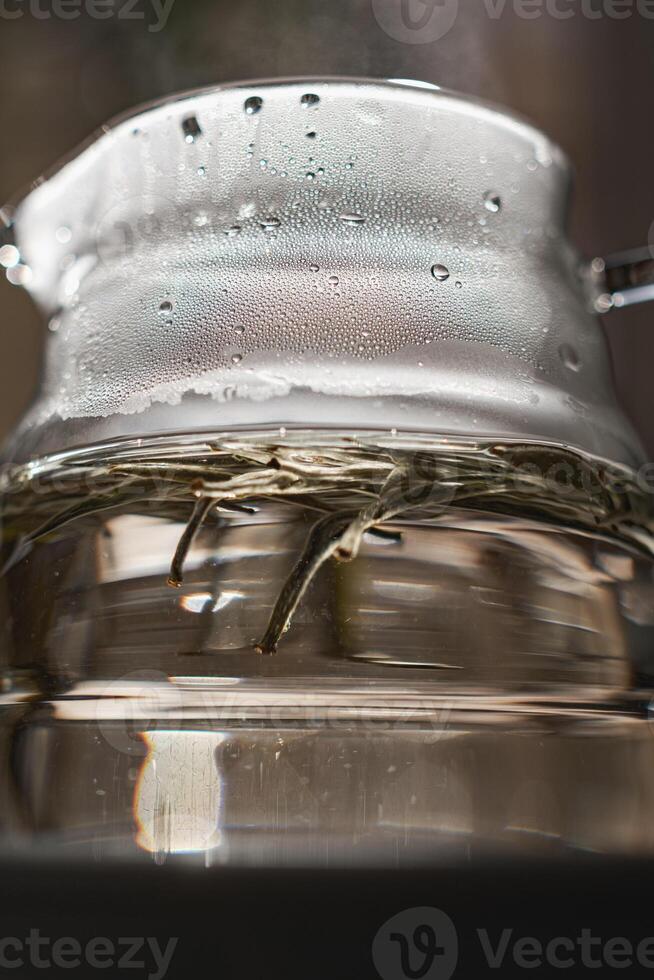 CloseUp of a Beautiful Teapot with Steam Rising Above and Fresh Tea Leaves Inside photo