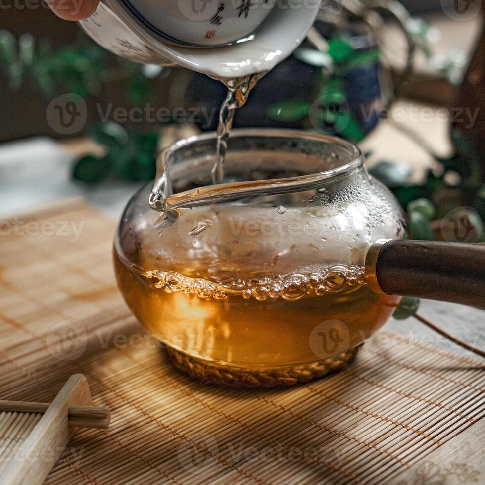 Tea is poured into a beautiful glass teapot, releasing delicate steam that dances above photo