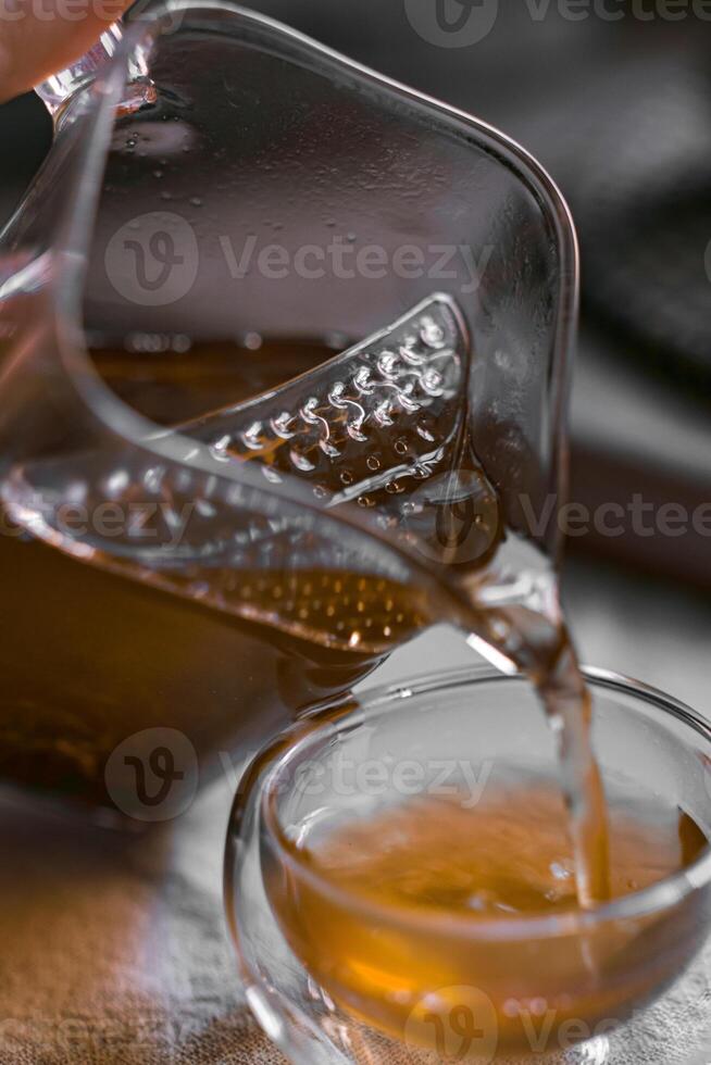 Pouring Tea from a Glass Pot into a Small Elegant Cup for a Refreshing Experience photo