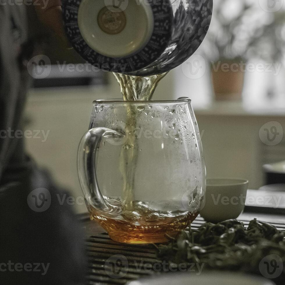 Pouring aromatic tea into a stylish glass cup filled with loose leaves is an artful experience photo