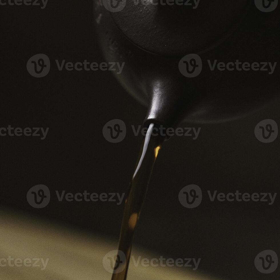 The Graceful and Elegant Pouring of a Rich, Dark Liquid from a Stylish and Beautiful Teapot photo