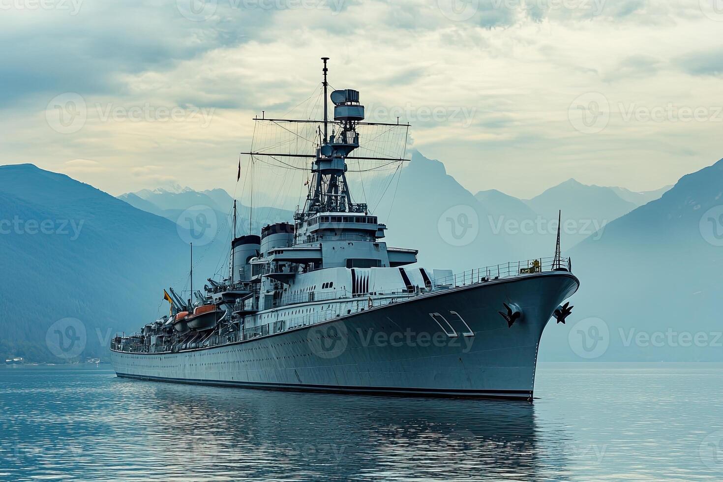 A battleship anchored in serene waters against mountains. photo