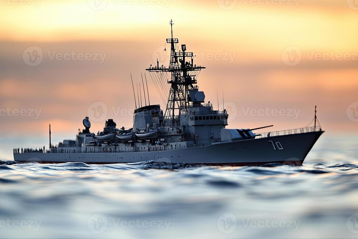 Naval warship sailing at sunset over calm waters. photo