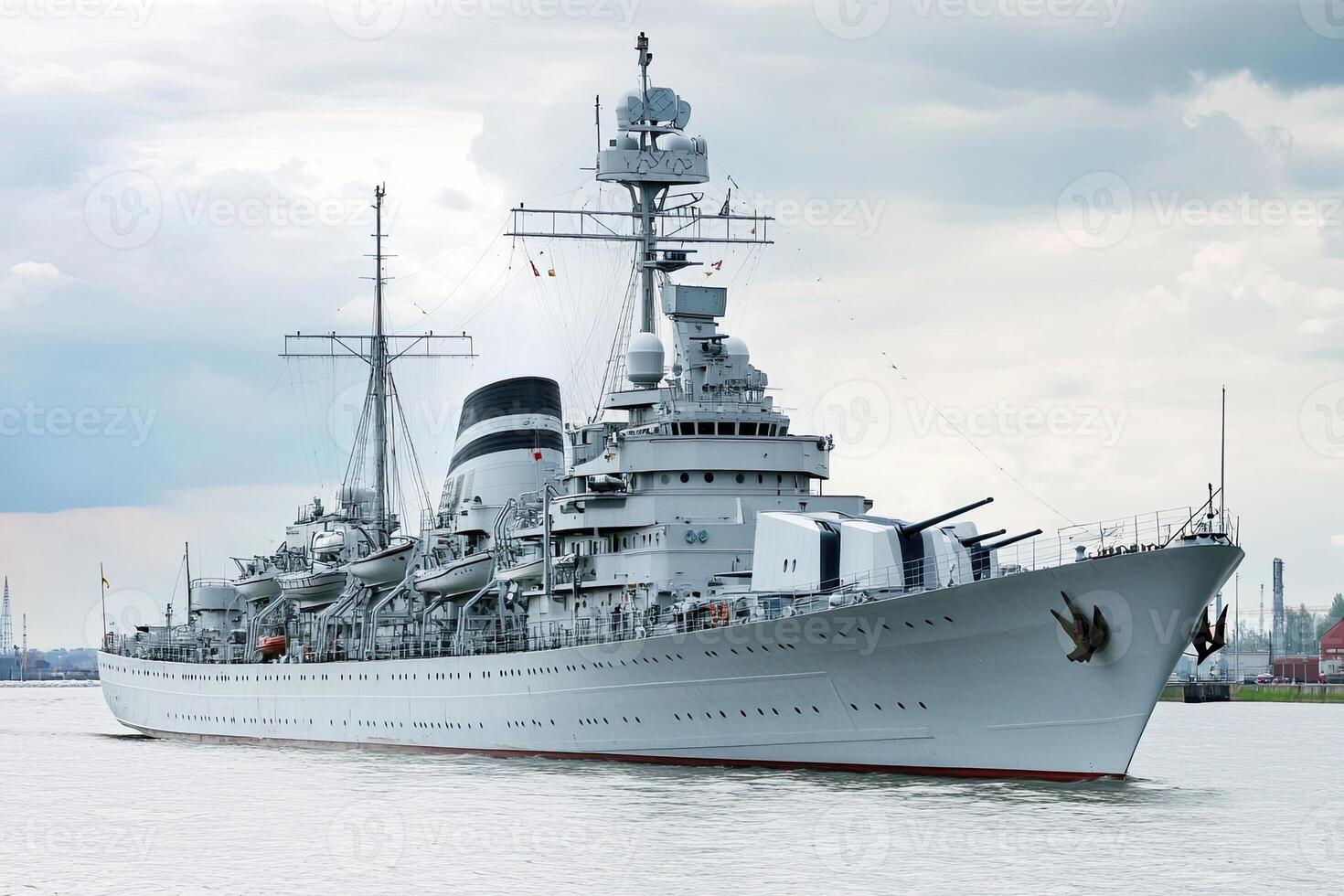 Military ship docked in a harbor under cloudy skies. photo