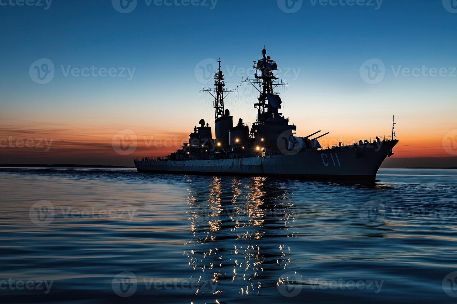 Warship silhouetted against a sunset over calm waters. photo
