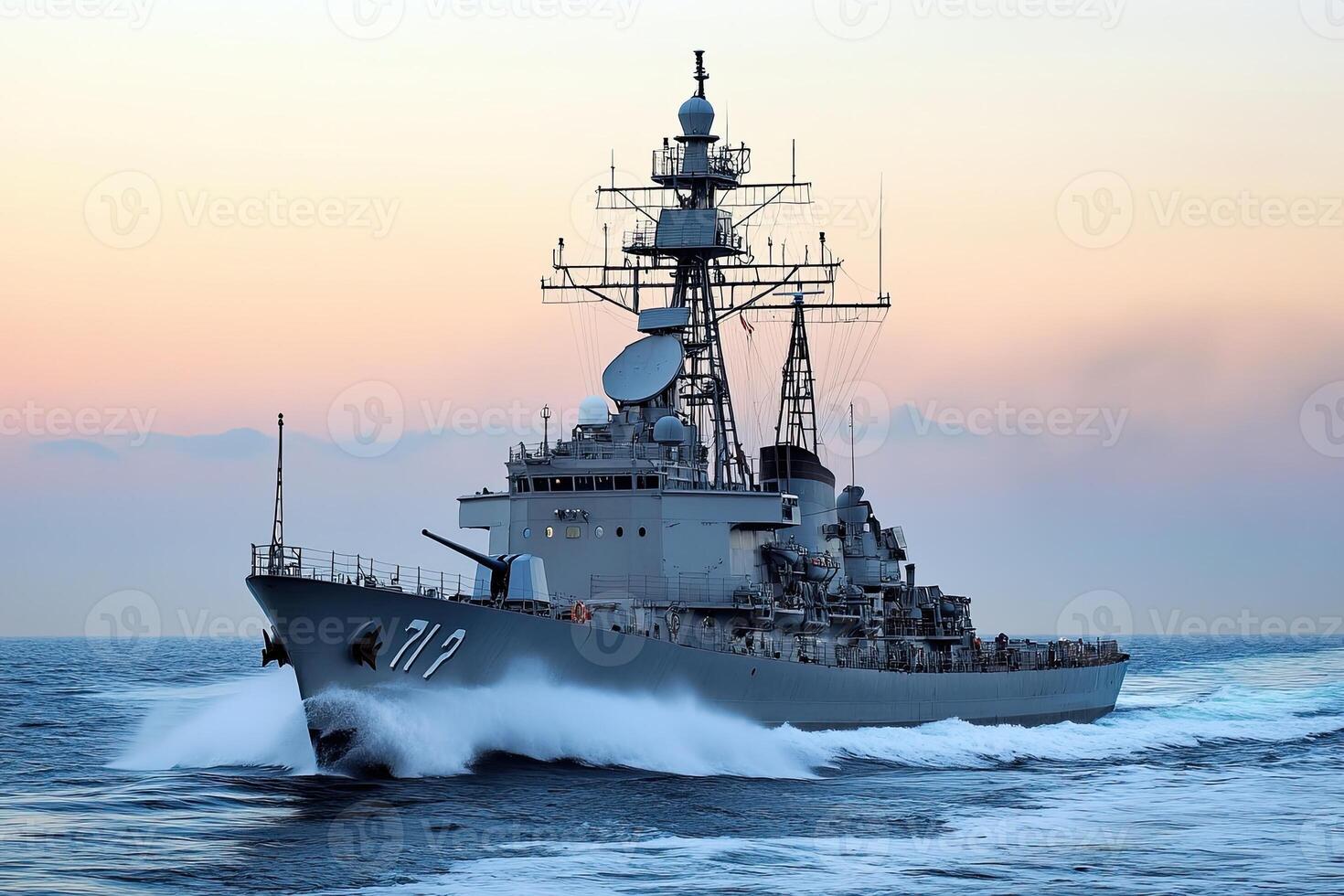 Naval ship navigating through ocean waves at sunset. photo
