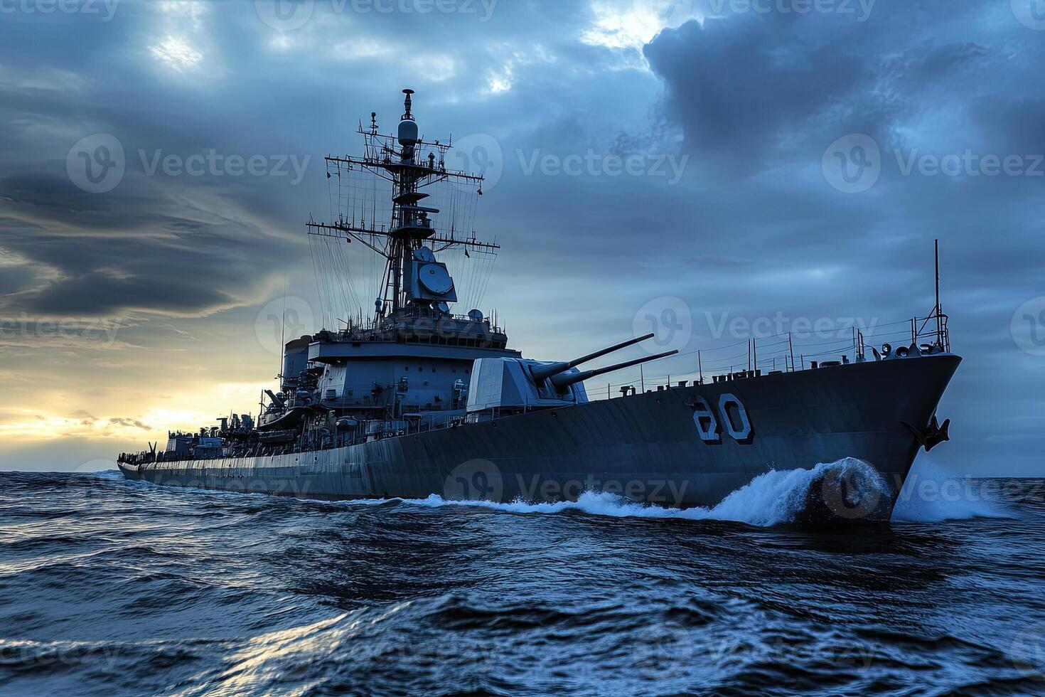 Military ship navigating through turbulent waters at sunset. photo