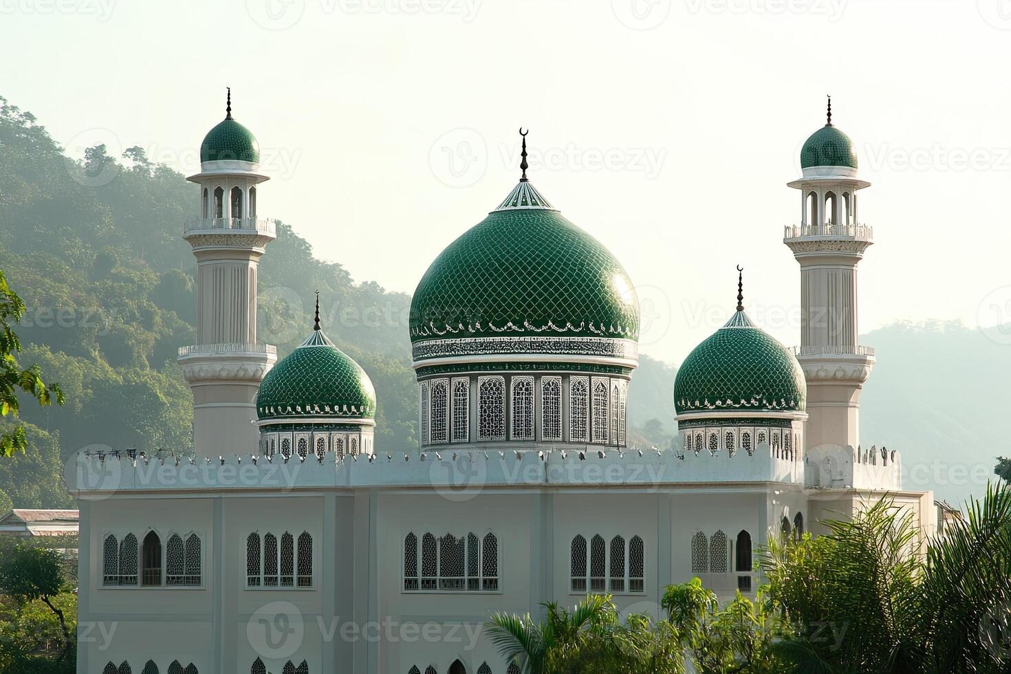 Elegant mosque with green domes and minarets against a mountain backdrop. photo