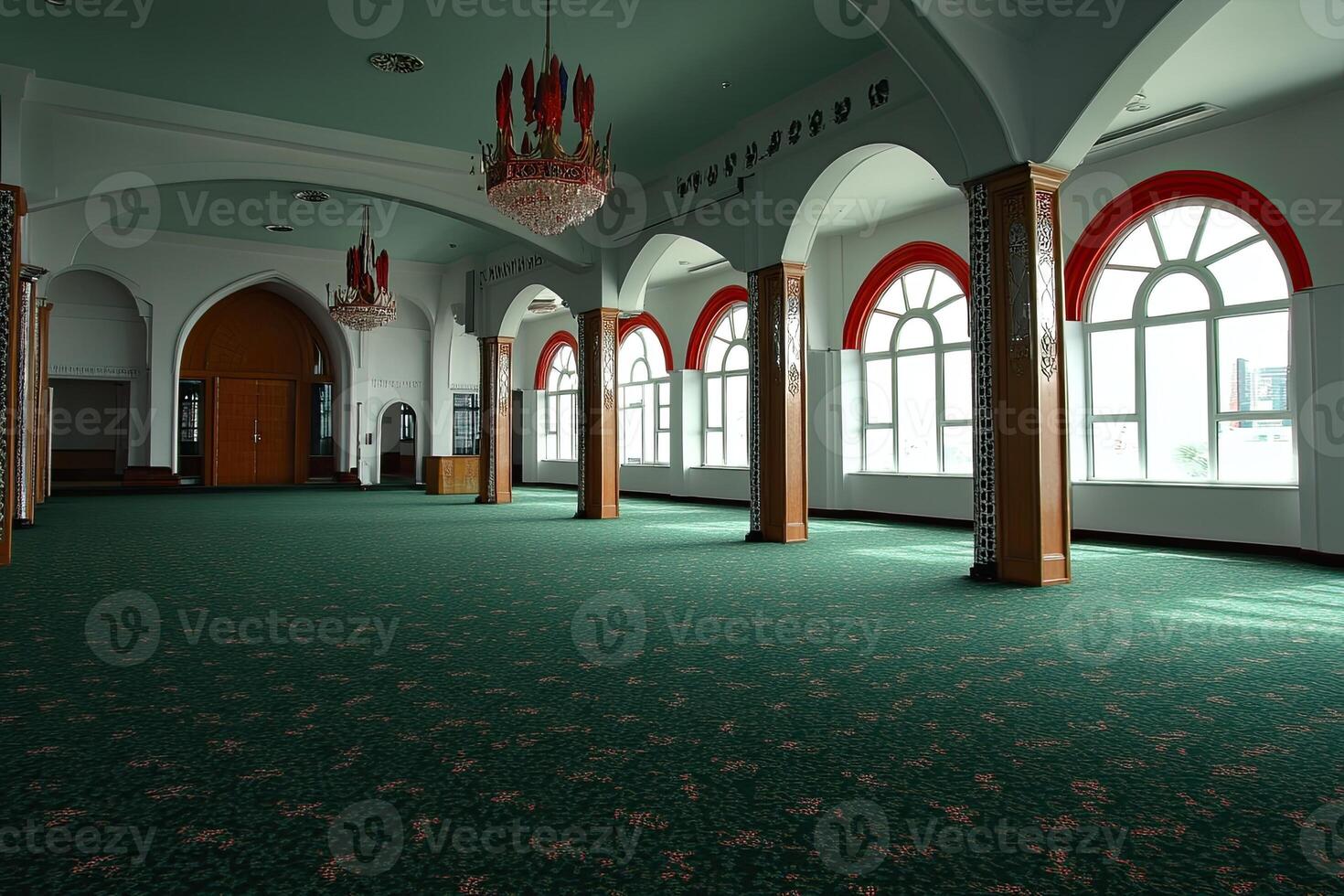 Empty mosque interior with arched windows, green carpet, and chandelier. photo