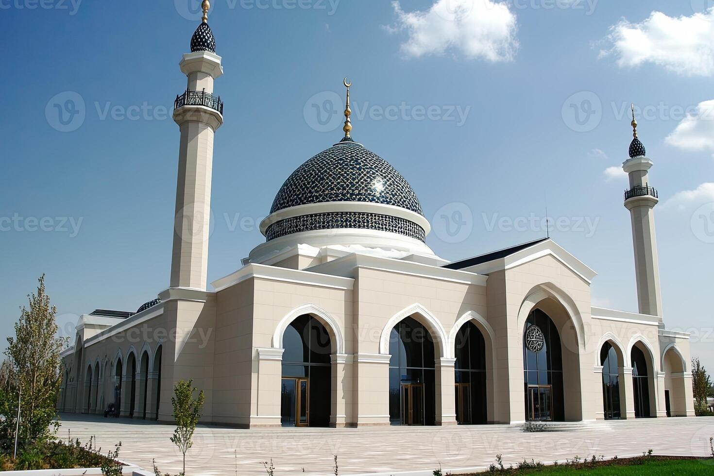 Majestic beige mosque with blue dome, two minarets, and arched entrances under a clear sky. photo