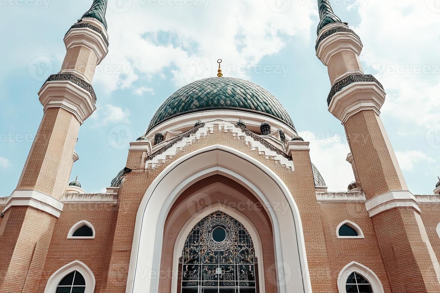 Low-angle view of a mosque's ornate facade, featuring a green dome, minarets, and intricate details. photo