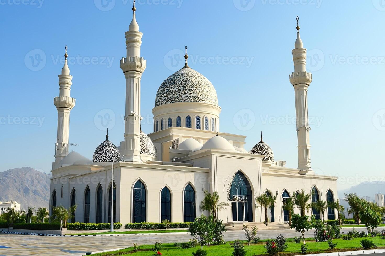 Majestic white mosque with twin minarets under a clear blue sky. photo