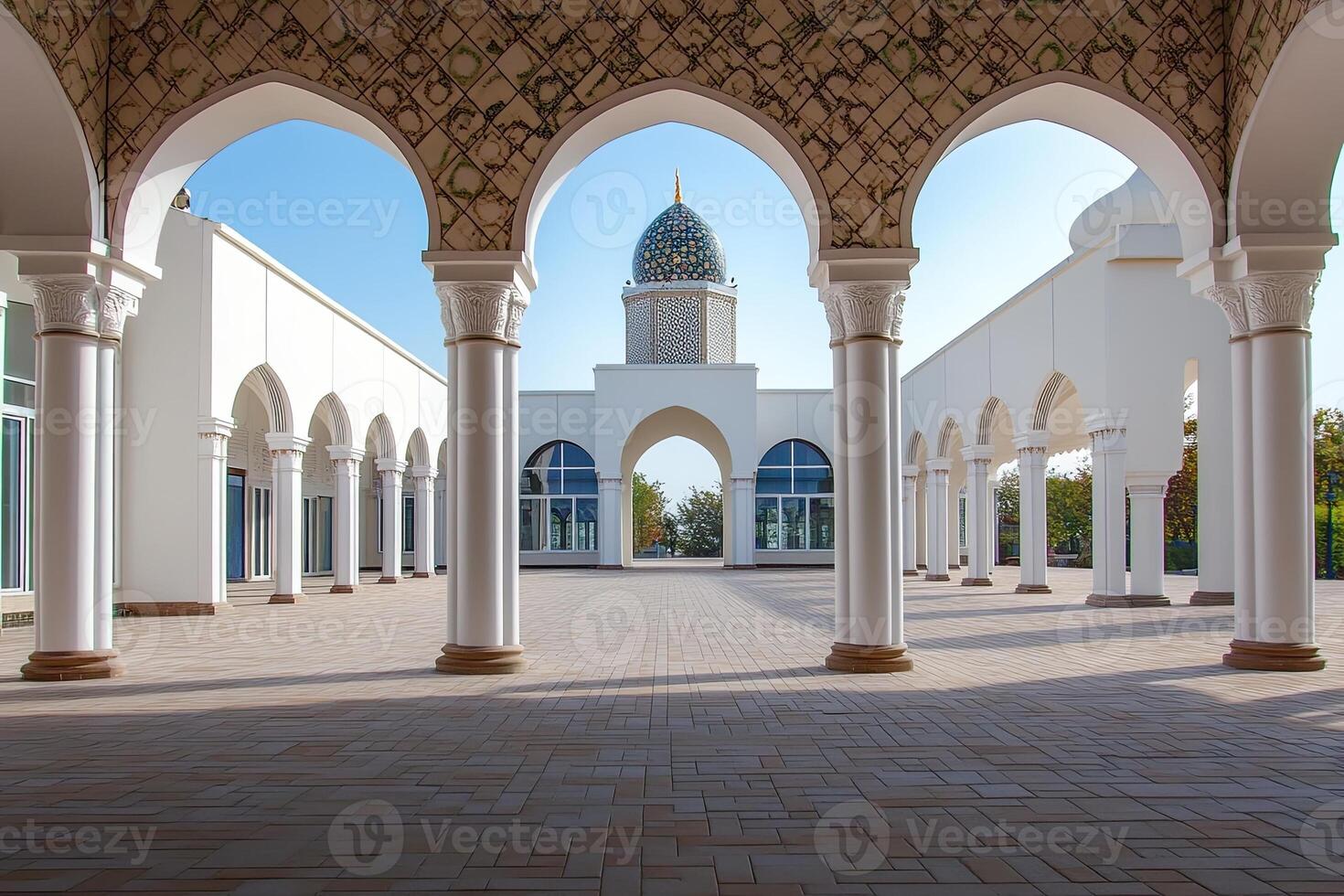 White mosque courtyard with arches, columns, and dome under a clear blue sky. photo