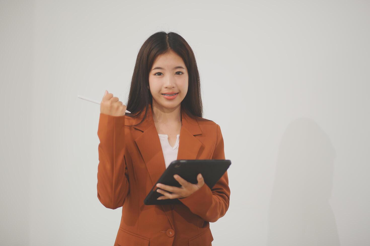 Young beautiful Asian woman in business office standing use tablet in hand, Thai girl enjoy browsing for online shopping store with copy space for advertisement, on isolated white background photo