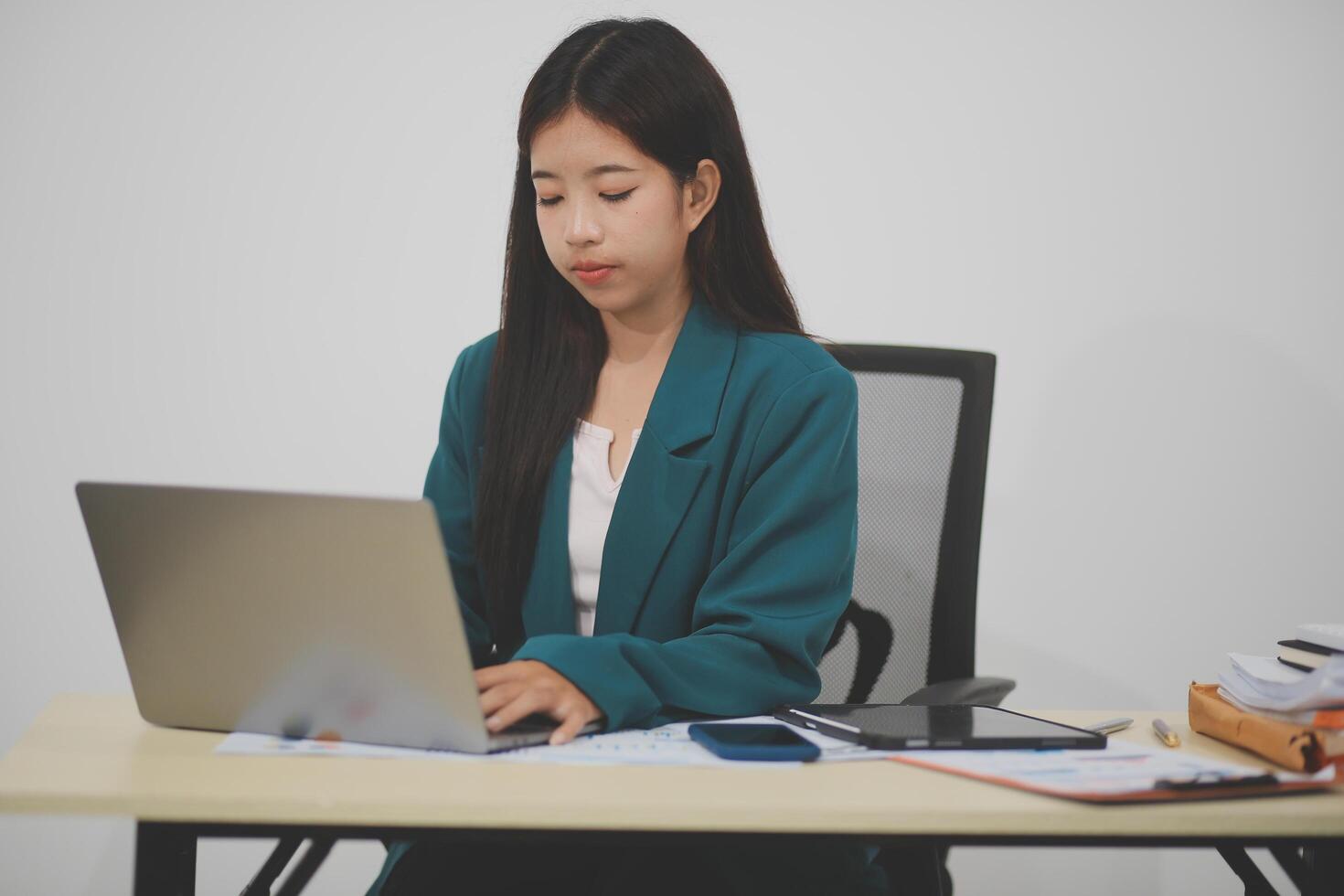 Beautiful Asian businesswoman work using a tablet and a laptop with documents placed at the office. photo
