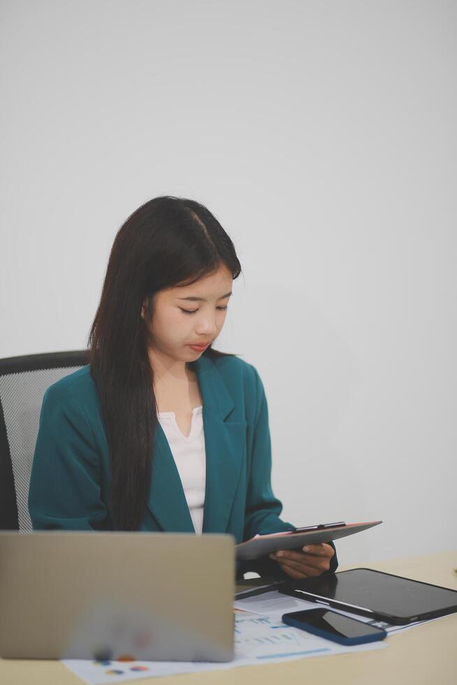 Asian business woman working using laptop computer, marketing report with calculator document on table Planning to analyze financial reports Investing in an online business plan, e-commerce. photo