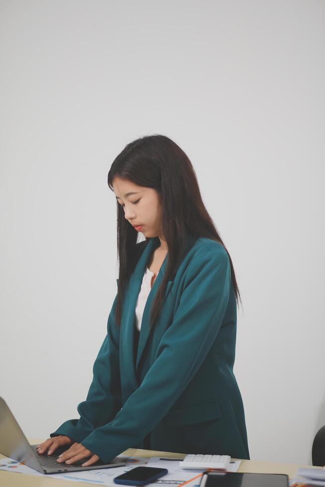 Asian Business woman using calculator and laptop for doing math finance on an office desk, tax, report, accounting, statistics, and analytical research concept photo