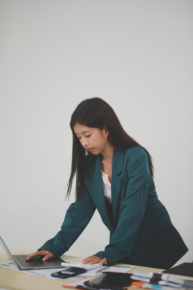 Asian Business woman using calculator and laptop for doing math finance on an office desk, tax, report, accounting, statistics, and analytical research concept photo