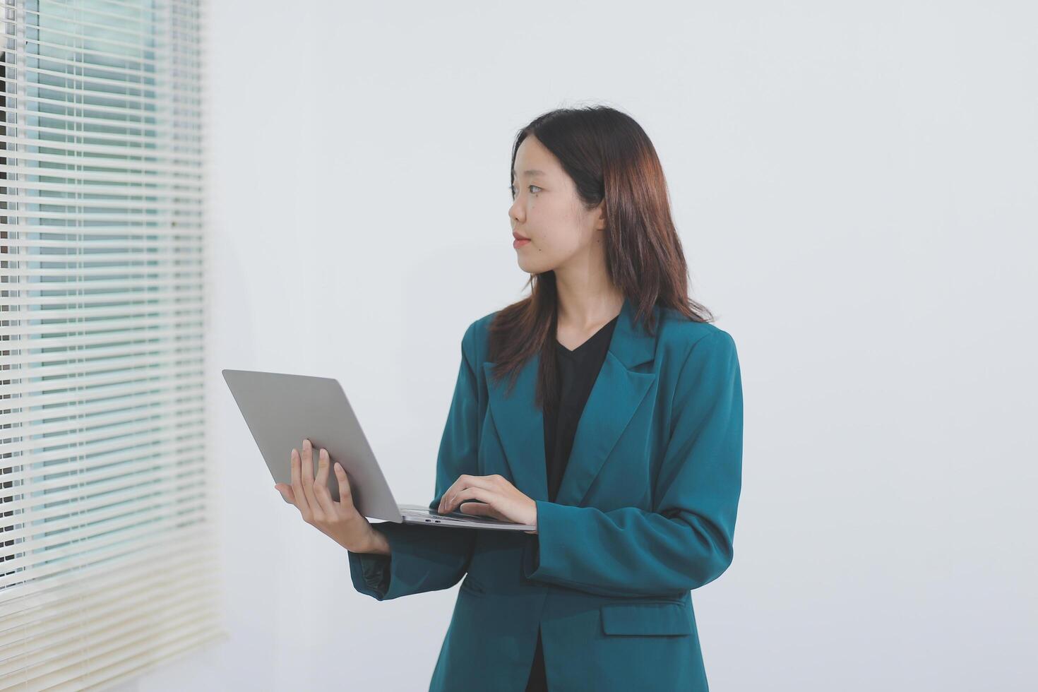 Attractive elegant young asian business woman using digital tablet standing on isolated background. Happy young latin female formal black suit holding tablet gadget working service with customer photo