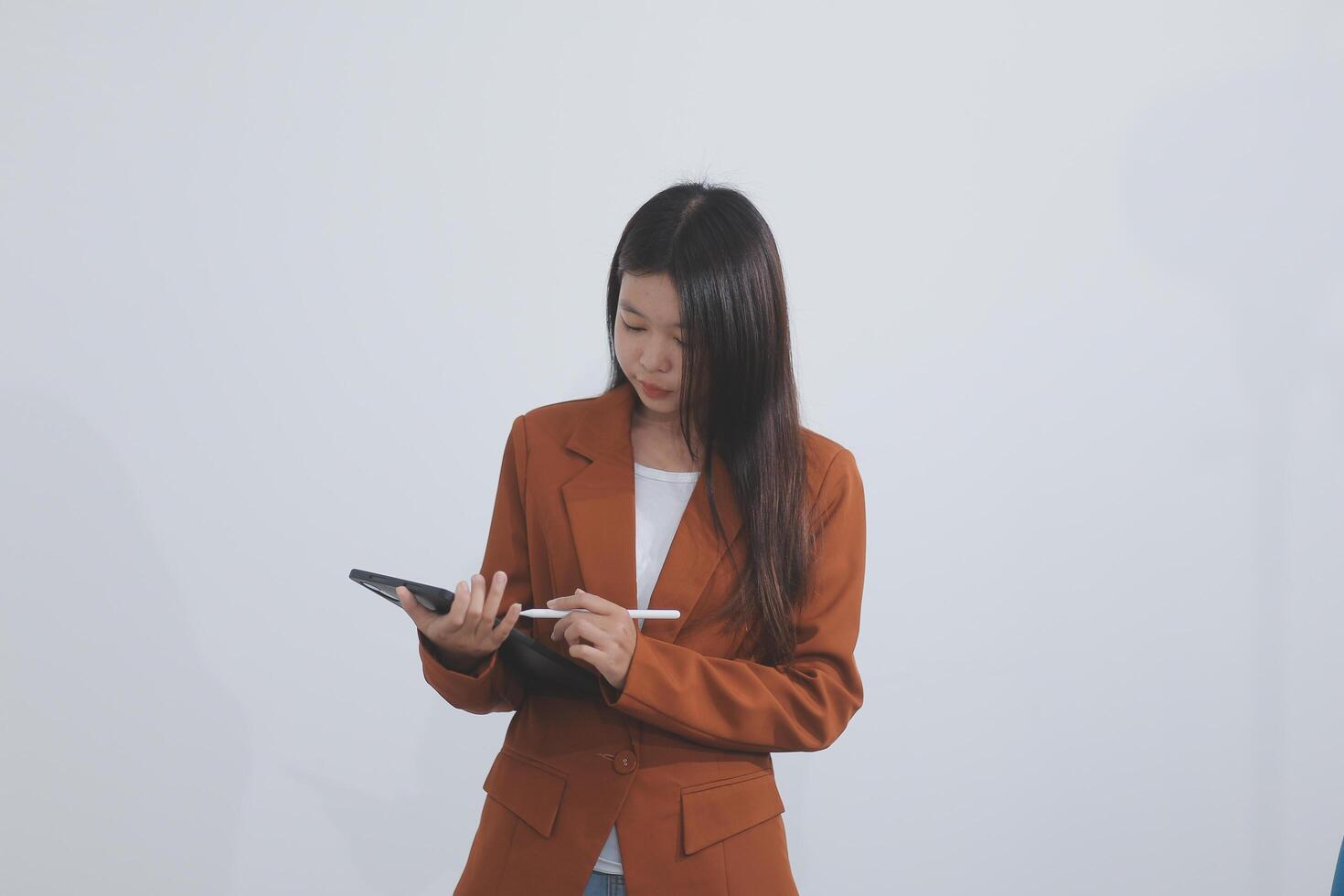 Attractive smiling Asian businesswoman standing holding tablet working and recording work details in office. photo