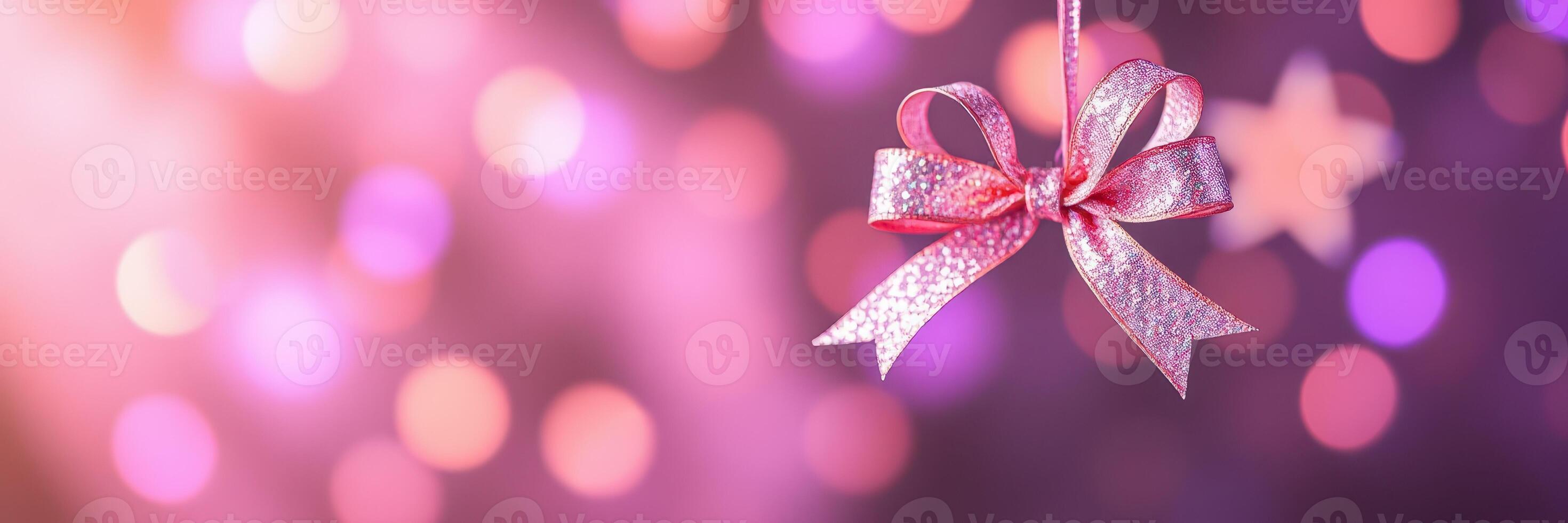 Delicate pink bow hanging against a vibrant bokeh background during a festive celebration photo