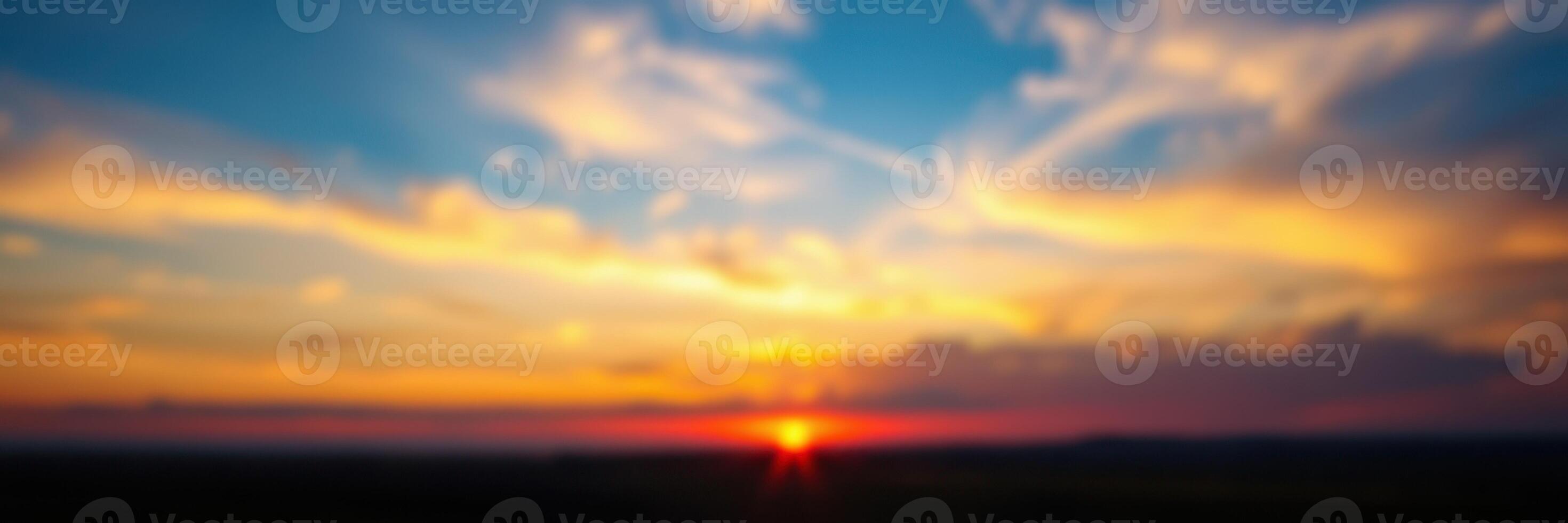 Colorful sunset over a horizon with vibrant clouds and a fading sun in the evening sky photo