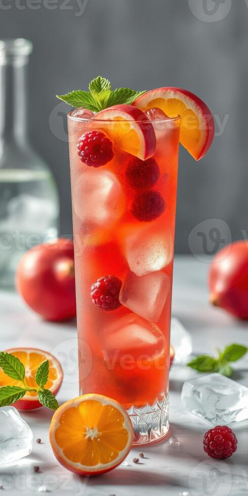 Refreshing summer drink with raspberries and citrus fruits in a tall glass on a marble countertop photo
