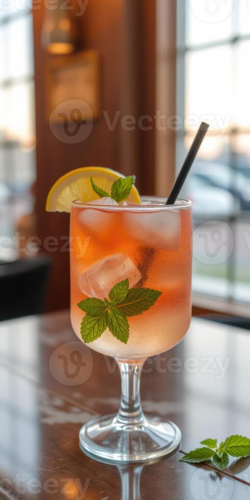 Refreshing drink served in a stylish glass garnished with mint and lemon in a cozy setting at sunset photo