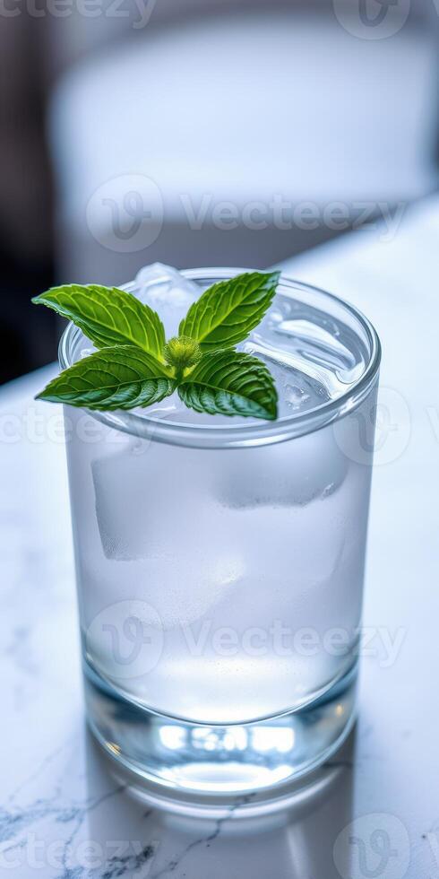 Refreshing mint drink with ice served in a clear glass on a marble table at a modern cafe photo