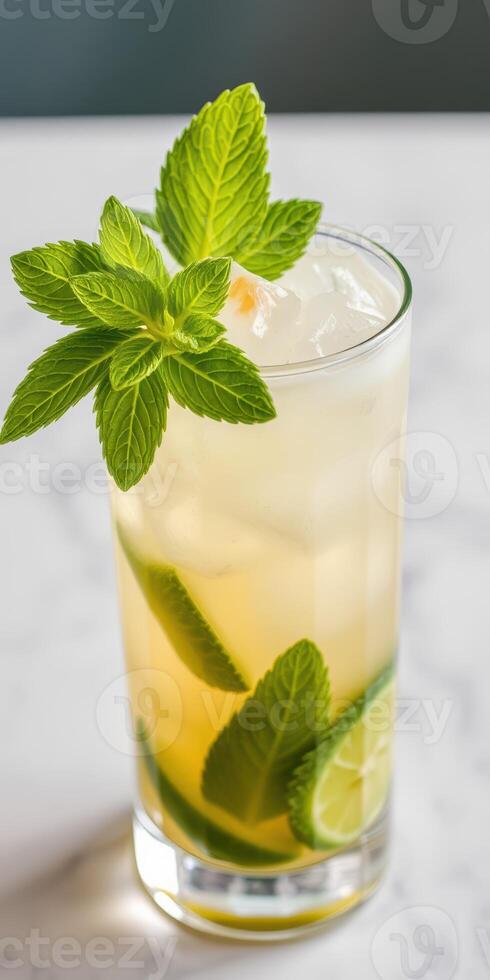 Refreshing mint and lime cocktail served in a tall glass with ice on a marble countertop photo