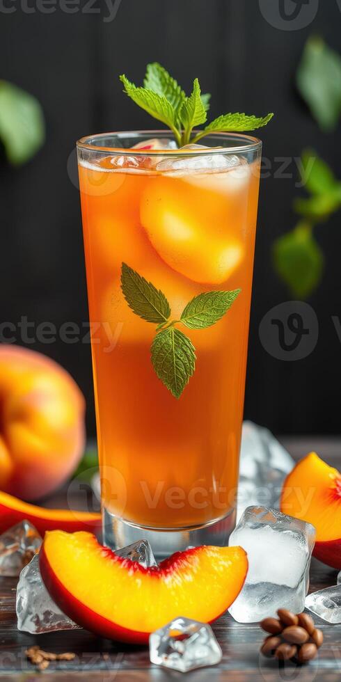 Refreshing peach iced tea in a tall glass garnished with mint leaves surrounded by fresh peaches and ice cubes photo