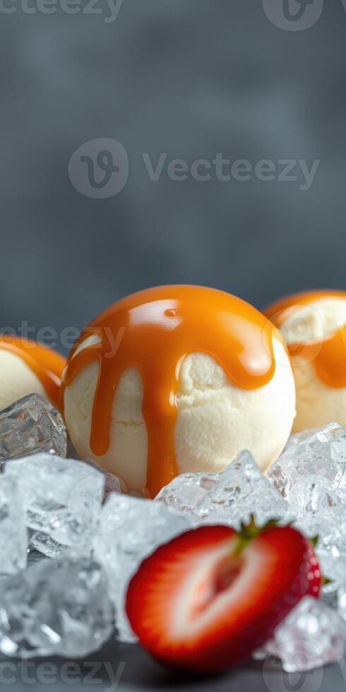 Delicious ice cream balls dripping with caramel sauce surrounded by ice and fresh strawberries photo
