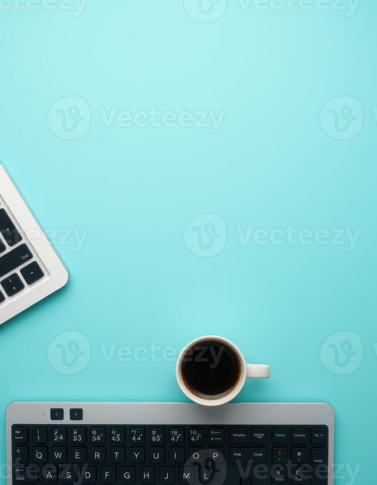 Workspace setup featuring a laptop, keyboard, and a cup of coffee on a vibrant blue desk photo