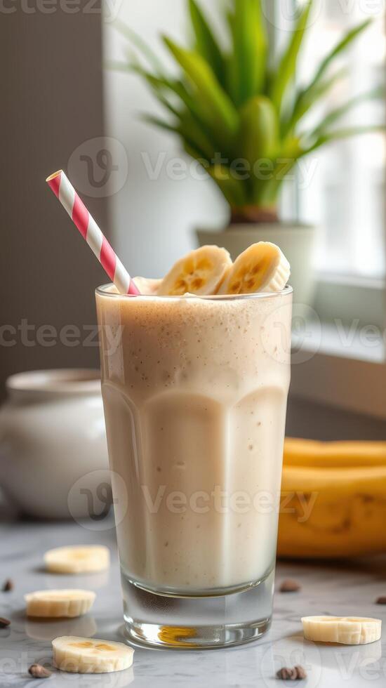Delicious banana smoothie served in a tall glass with a pink striped straw and fresh banana slices photo