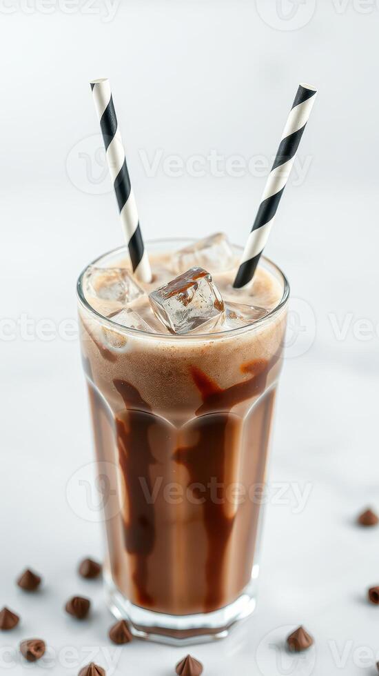 Refreshing chocolate drink served in a tall glass with ice cubes and striped straws on a marble table photo