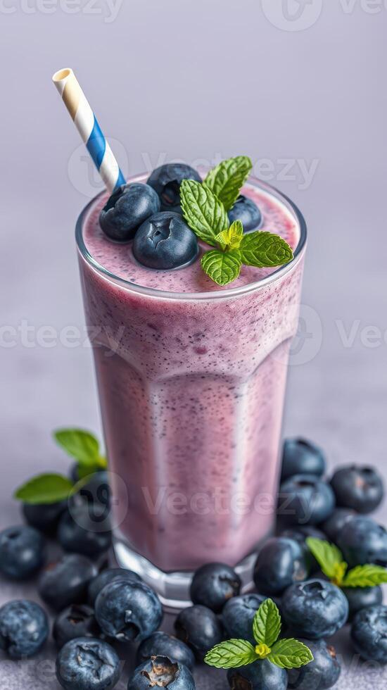 Smoothie prepared with fresh blueberries and mint served in a tall glass with a striped straw photo