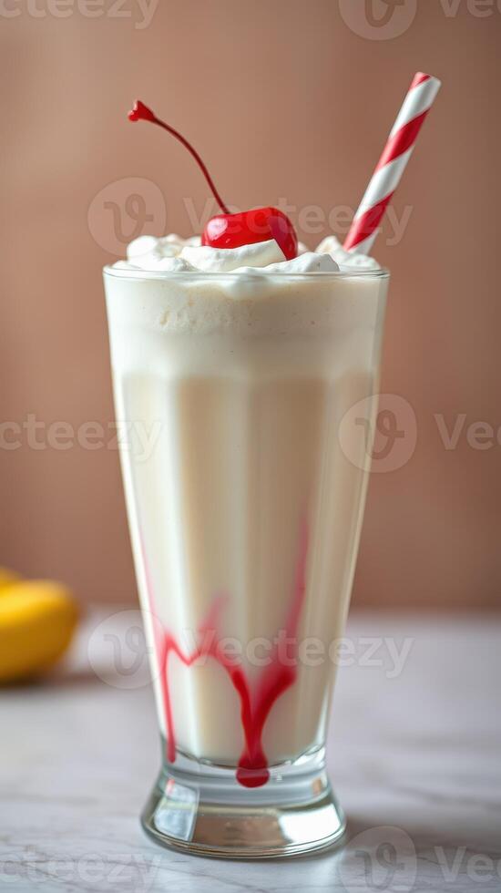 Classic banana milkshake with whipped cream and cherry served in a tall glass photo