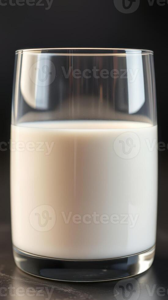 Close up of a glass filled with fresh milk against a dark background in a well-lit setting photo