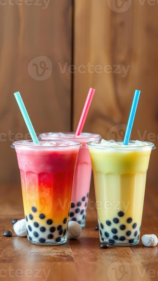 Colorful bubble tea drinks in clear cups on a wooden table with colorful layers and tapioca pearls photo