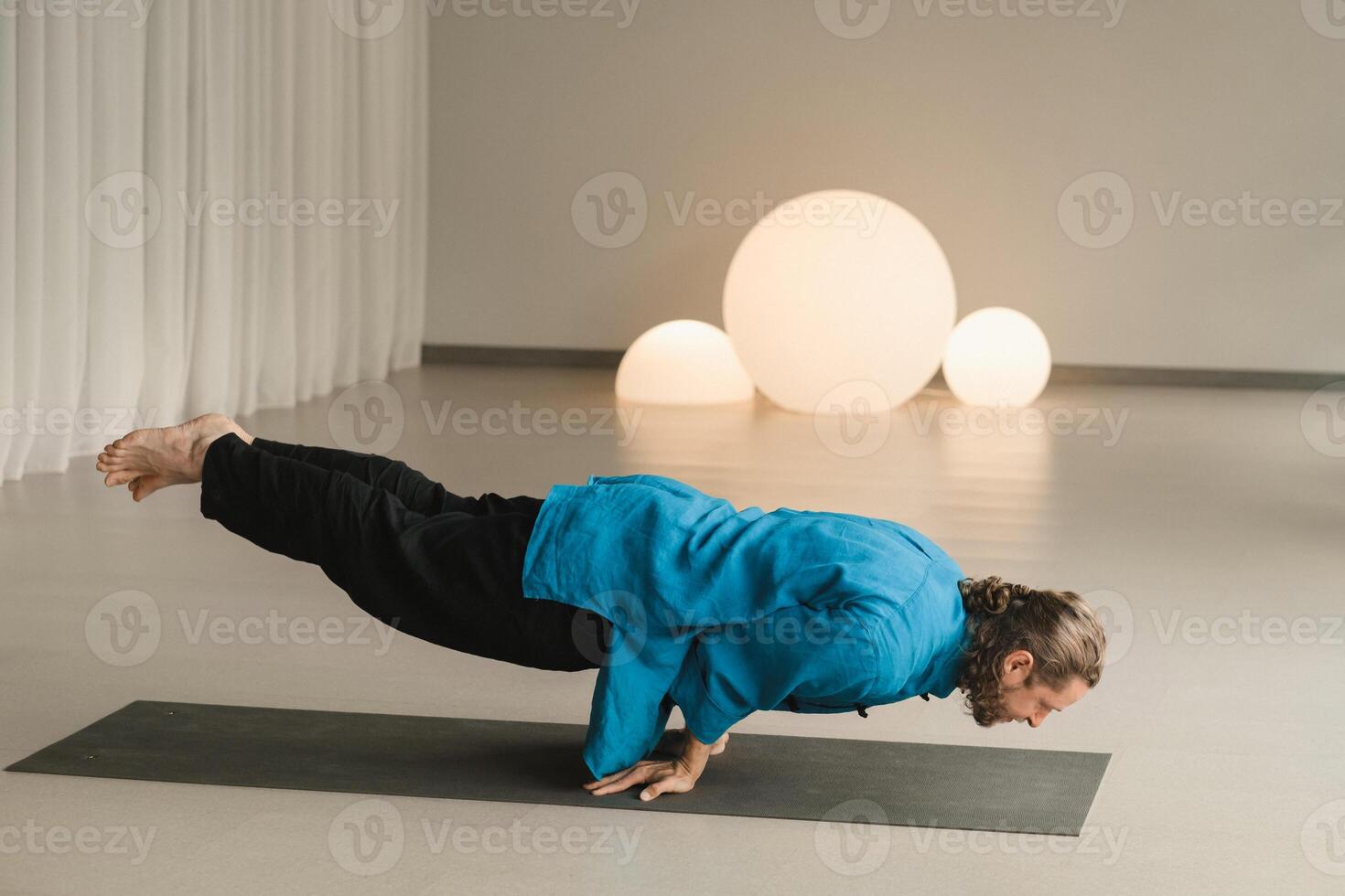 A man in a blue kimono does yoga indoors. Healthy lifestyle photo