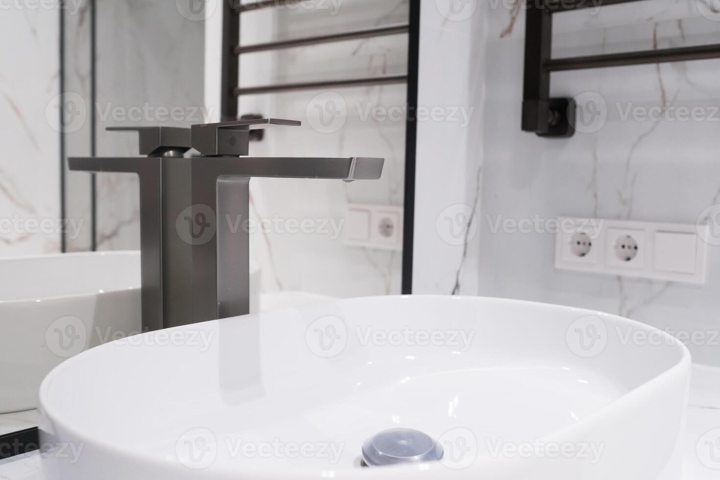 Chrome water faucet and white pedestal sink in bathroom . Stylish bathroom photo