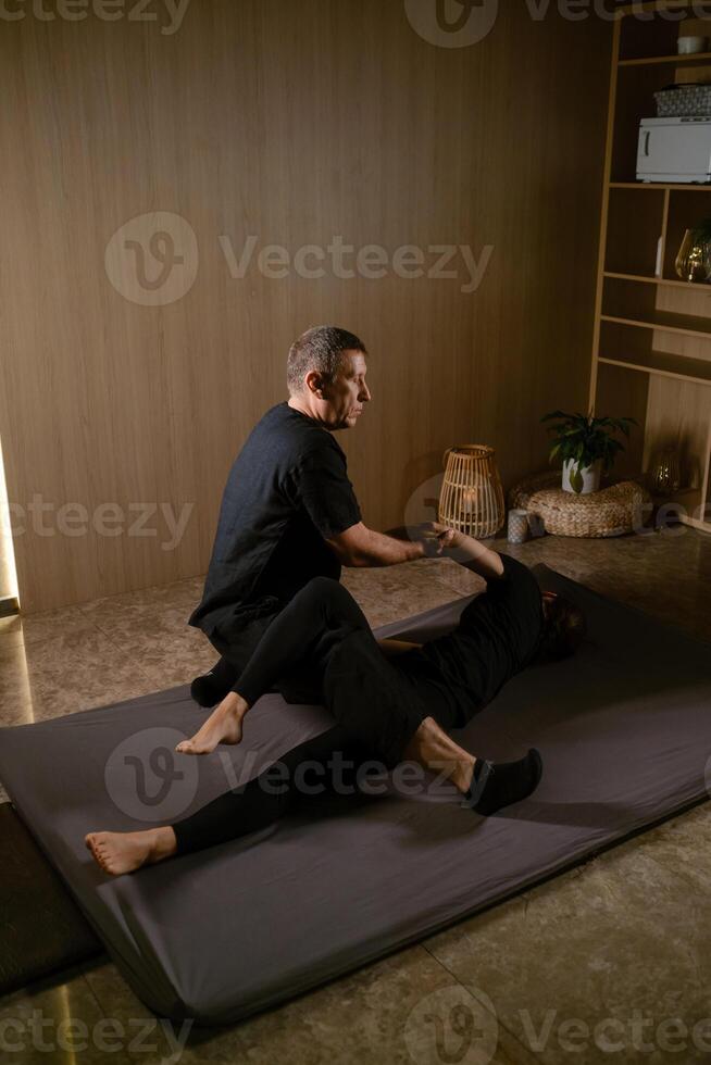 Girl in Thai massage session from therapist in massage room . Traditional Asian stretching therapy photo