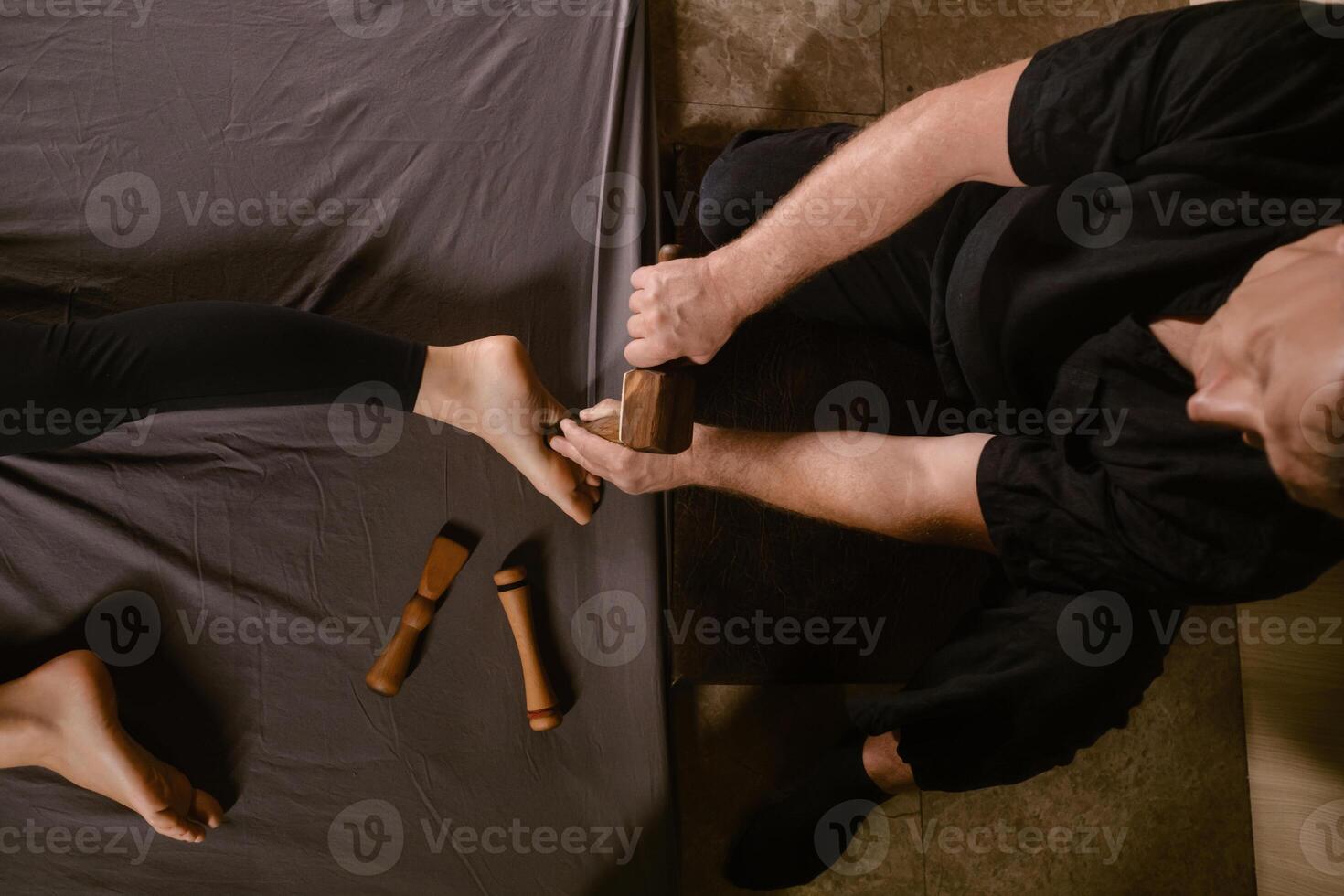 A man gives a relaxing Thai foot massage with a Tok-Sen massage kit at a beauty spa. Body care photo