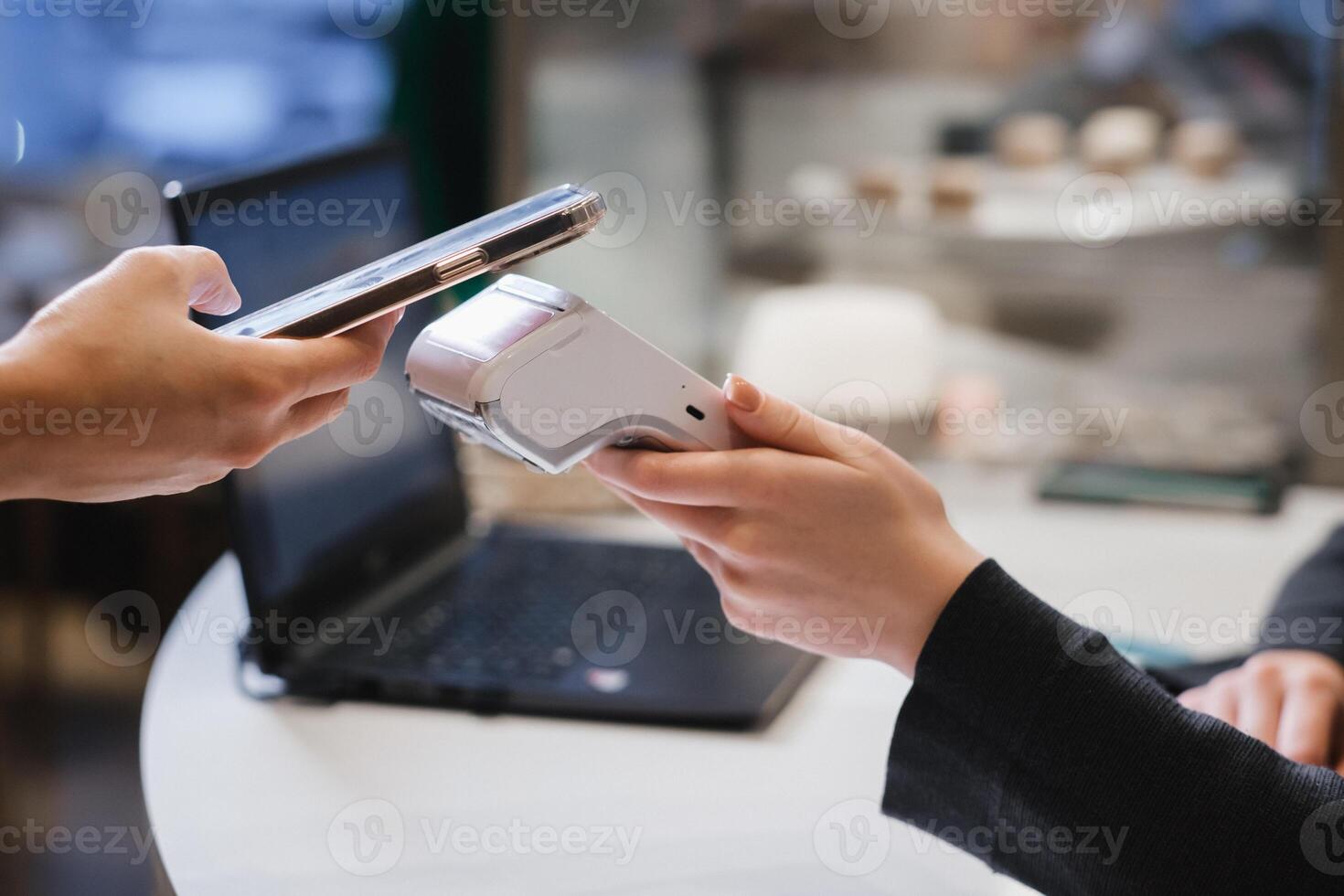 A customer uses his phone to pay through a terminal . Concept of cashless technologies and money transfers photo
