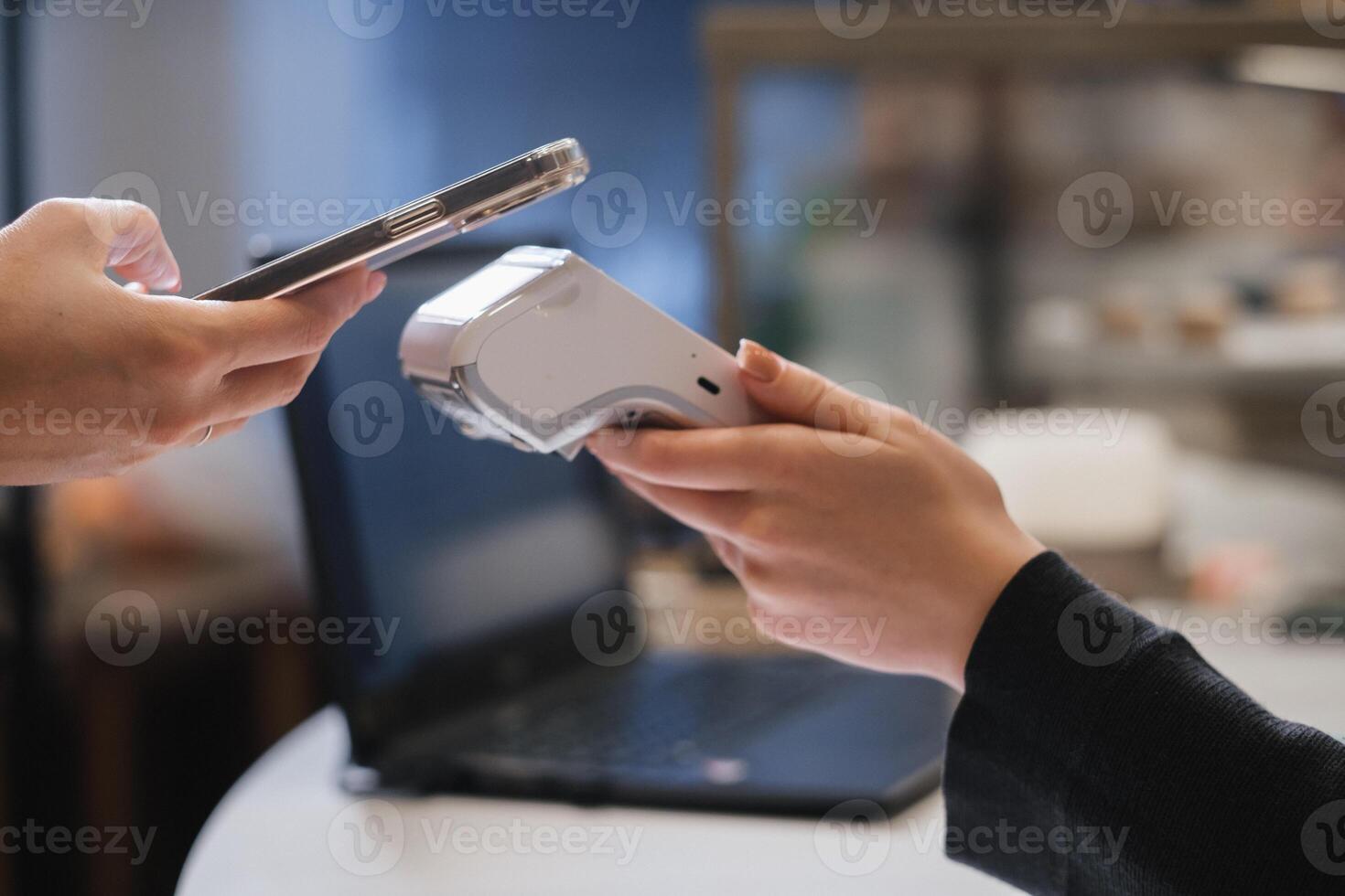 A customer uses his phone to pay through a terminal . Concept of cashless technologies and money transfers photo