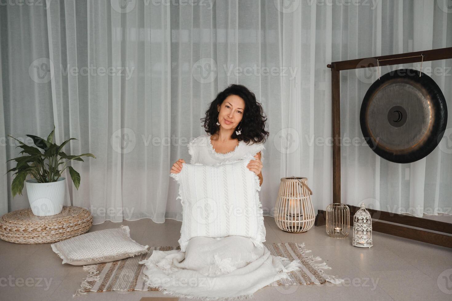 Woman in white clothes holding a pillow sitting in a fitness club class . The concept of a women's circle photo